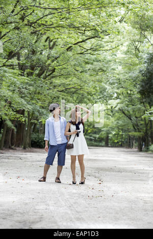 Una coppia di uomo e donna in un parco di Kyoto in un viale di alberi maturi. Foto Stock