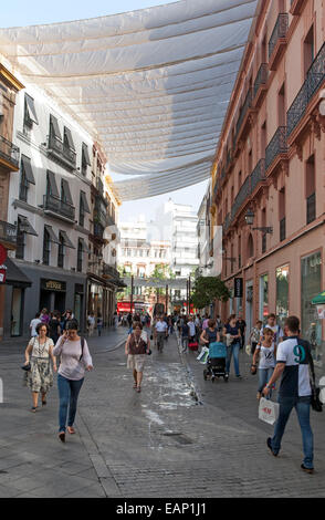 Tessuto diffuso su edifici per fornire ombra nella trafficata via dello shopping nel centro di Siviglia, Spagna Foto Stock