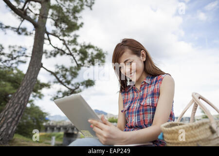 Giovane donna con una tavoletta digitale nel parco. Foto Stock