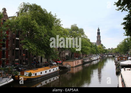 Casa barche lungo il canale Prinsengracht con edificio storico del XVII secolo Westerkerk nel quartiere Jordaan, centro di Amsterdam, Paesi Bassi in background Foto Stock