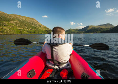 Un uomo di mezza età paddling in un kayak inflateable sull'Ullswater nel distretto del lago, UK. Foto Stock