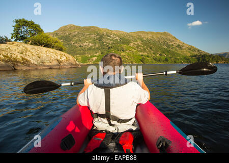 Un uomo di mezza età paddling in un kayak inflateable sull'Ullswater nel distretto del lago, UK. Foto Stock