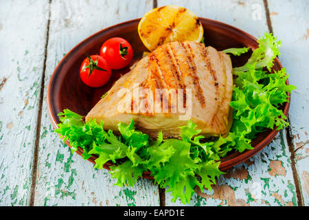 Grigliata di pesce di filetto con limone e pomodori ciliegia Foto Stock