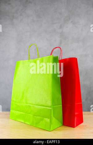 Il verde e il rosso carta Shopping Bags su legno Store TAVOLO. Foto Stock