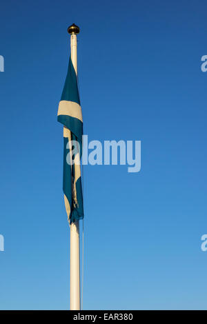 Bandiera della Scozia, noto anche come Saint Andrew's Cross o si intraversa, cada su una bandiera bianca la pole con un cielo blu dietro Foto Stock