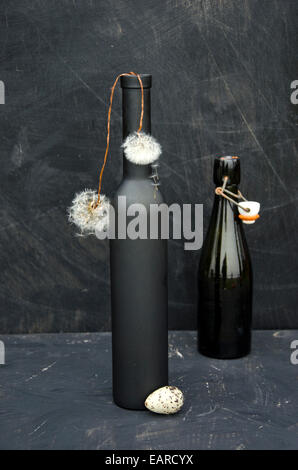 Still-life con bottiglie nere, uova di uccello e semi di dente di leone Foto Stock