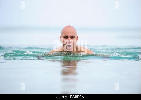 L'uomo, inizio 40s, facendo breaststrokes attraverso il mare Foto Stock