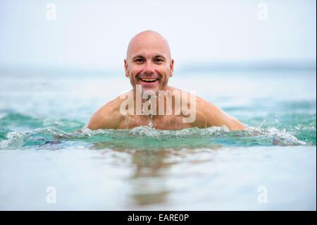 L'uomo, inizio 40s, facendo breaststrokes attraverso il mare Foto Stock