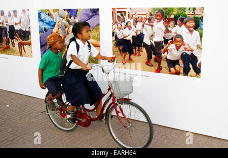 Phnom Penh Cambogia. Xx Nov, 2014. Una scolaretta e un ragazzino ride passato le foto scattate dai bambini durante una mostra a Phnom Penh in Cambogia, nov. 20, 2014. Un mese di esposizione per i bambini le foto di calci fuori qui giovedì a segnare la Giornata Universale dei Bambini. © Sovannara/Xinhua/Alamy Live News Foto Stock