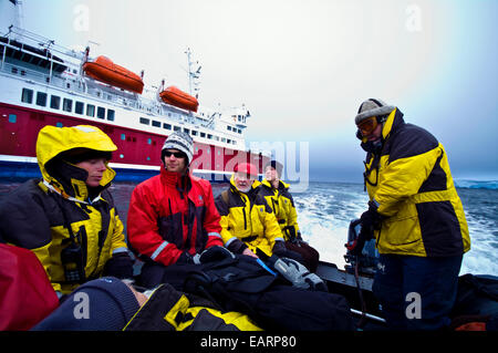 Una spedizione in Antartide equipaggio in giacche impermeabili in una barca Zodiac. Foto Stock