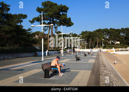 Uomo di mezza età seduta sul banco di lavoro con shirt off sul lungomare Foto Stock