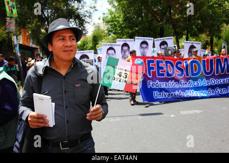 La Paz, Bolivia. 20 novembre 2014. Un manifestante detiene una bandiera messicana con 43 Ayotzinapa su di essa durante una marcia per chiedere giustizia per i 43 studenti scomparsi in Messico e protestare contro la gestione del caso da parte del governo messicano. Oggi è stata designata giornata globale d'azione per Ayotzinapa; è previsto uno sciopero nazionale in Messico e molte proteste stanno avendo luogo in tutto il mondo per mostrare sostegno. Gli studenti sono scomparsi dopo essersi scontrati con la polizia nella notte del 26 settembre nella città di Iguala. Il banner è per la UMSA University Federation of Teachers/professors Trade Union Foto Stock