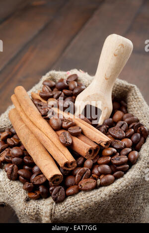 Sacco con i chicchi di caffè e cannella, scoop di legno Foto Stock