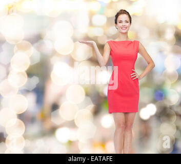 Sorridente giovane donna nel vestire qualcosa di contenimento Foto Stock