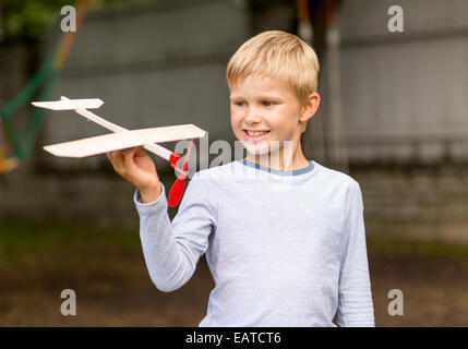 Sorridente ragazzino tenendo un legno modello di aeroplano Foto Stock