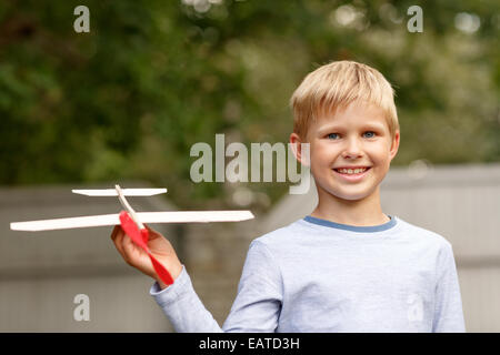 Sorridente ragazzino tenendo un legno modello di aeroplano Foto Stock