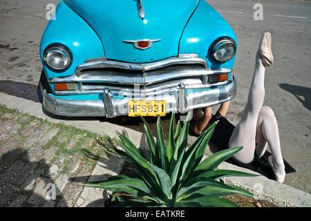 Un classico balletto cubano ballerina che fissa una vecchia vettura americana. Foto Stock