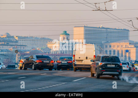 Sun a Mosca, in Russia. Giovedì 9 Novembre 20, 2014. Meteo: Sun, lo smog e il gelo a Mosca, in Russia. La temperatura è piuttosto freddo, fino a -11°C (12,2°F). O nuvoloso o soleggiato, nessuna neve a tutti e praticamente nessun vento. Così le regole di smog il giorno e trasporti aggiunge i suoi gas di scarico per l'aria di città al di sopra di tutto il resto. Traffico oltre il grande ponte di pietra sul fiume di Mosca. Edifici di Stato russo Libreria in background (a destra). Credito: Alex Immagini/Alamy Live News Foto Stock