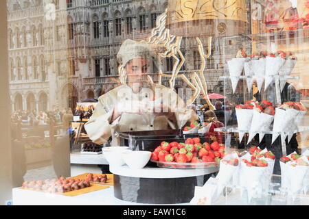 Edifici situati sulla Grand Place riflettere sul shop store window belga di cioccolato Godiva shop & commessa. Foto Stock