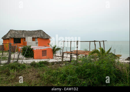 Casa messicana fronte mare con tradizionale tetto di paglia e pareti in stucco dipinte di arancio. Foto Stock