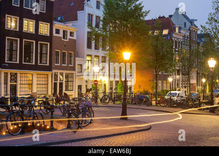 Le luci da una bicicletta passando su un angolo della Prinsengracht e Blauwburgwal di notte, Amsterdam, Olanda Settentrionale, Paesi Bassi Foto Stock