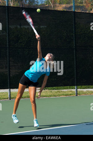 Junior ragazza competitivo il giocatore di tennis la visualizzazione di un servizio eccellente tecnica. Motion Blur. Foto Stock