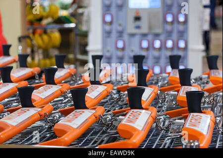 Carrelli per supermercati di fronte a un rack con un palmare subito self-dispositivi di scansione in un supermercato Migros di Zurigo, Svizzera. Foto Stock