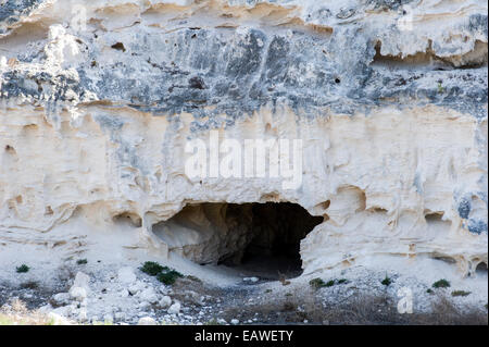 Una caverna-tunnel come entrata conduce ad una prigione di cava di calcare in una scogliera. Foto Stock