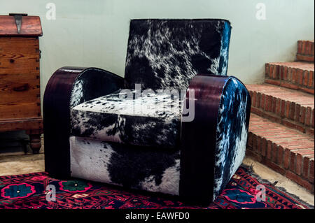 Un invitante Nguni elegante sedia di pelle in una cantina guest lounge. Foto Stock