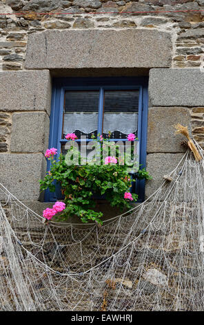 Una tipica St Suliac casa : vedova con gerani fiori, con la parete decorata con una rete da pesca. Foto Stock
