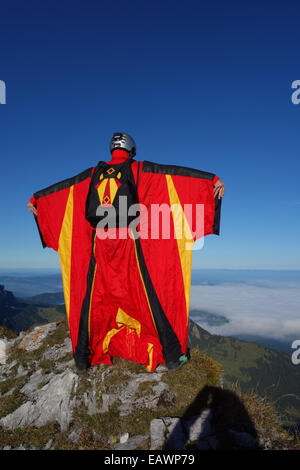 Ponticello di base sta uscendo da una rupe verso il basso nella profonda valle. In tal modo egli è entro una wingsuit a tariffa volare lontano dalla roccia. Foto Stock