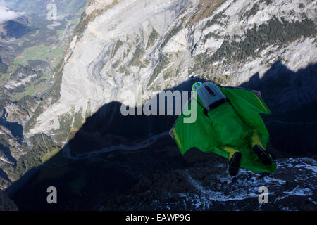 Ponticello di base sta uscendo da una rupe verso il basso nella profonda valle. In tal modo egli è entro una wingsuit a tariffa volare lontano dalla roccia. Foto Stock