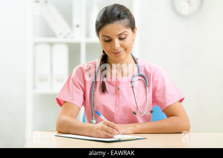 Medico donna seduta alla scrivania in Doctor's room Foto Stock