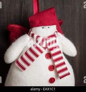 Fatto a mano feltro pupazzo di neve decorazione di Natale. Giocattolo di natale. In stile vintage, su uno sfondo di legno. Foto Stock