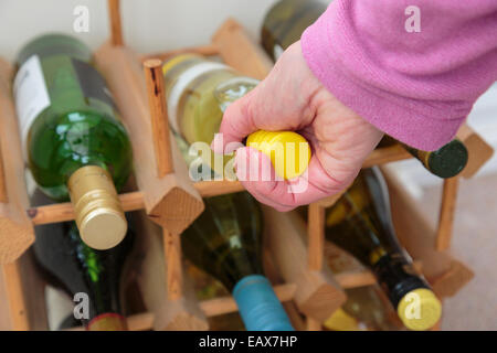 Scena quotidiana dove una donna sceglie una bottiglia di vino bianco da bere da una cantina di vini diversi a casa. Concetto di stile di vita. Inghilterra Regno Unito Gran Bretagna Foto Stock