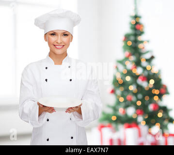 Donna sorridente chef con piastra vuota Foto Stock