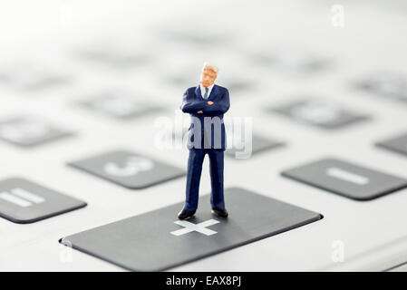 Imprenditore figurina permanente sulla calcolatrice Foto Stock