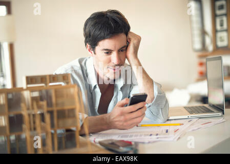 Imprenditore tramite telefono cellulare alla scrivania Foto Stock