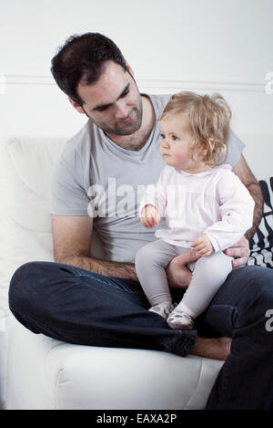 Padre holding Baby girl su lap Foto Stock