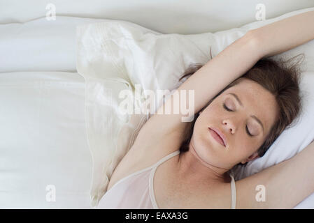 Donna giaceva a letto stretching le braccia sopra la testa Foto Stock