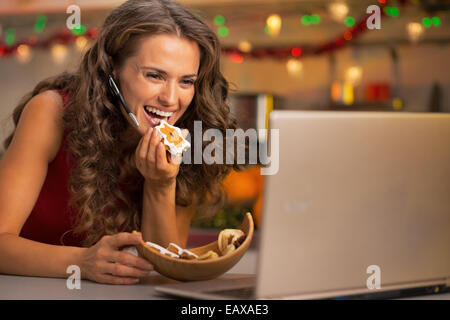 Felice giovane donna con biscotti di Natale con la video chat su laptop Foto Stock