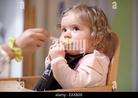 Baby girl essendo alimentato dalla casa madre, ritagliato Foto Stock