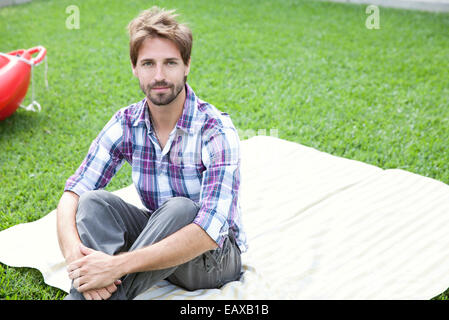 Uomo seduto su una coperta all'aperto Foto Stock