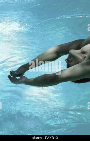Uomo appoggiato all'indietro oltre la piscina, a braccia alzate Foto Stock