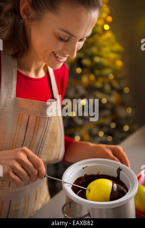 Giovani casalinga che rendono Apple in glassa di cioccolato Foto Stock