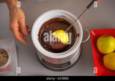 Giovani casalinga che rendono Apple in glassa di cioccolato Foto Stock