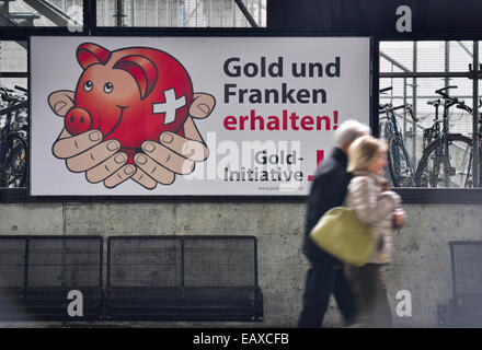 Zurigo, Svizzera. Xxi Nov, 2014. Persone alla stazione principale di Zurigo sono passando dalla campagna referendaria dei poster di Swiss 'Gold iniziativa' referendum che si terrà il Nov 30, 2014. Con una settimana a visitare la campagna referendaria del Swiss 'Gold iniziativa' sta andando a piena potenza in tutta la Svizzera. Il controverso referendum è volto a forzare la Banca Nazionale Svizzera per tenere almeno il 20% di tutti i beni in oro fisico. Credito: Erik Tham/Alamy Live News Foto Stock
