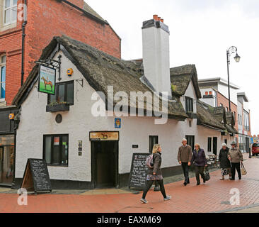 Storico del xvii secolo del cavallo e del fantino pub con pareti dipinte di bianco e tetti in paglia con gente camminare passato - a Wrexham, Galles Foto Stock