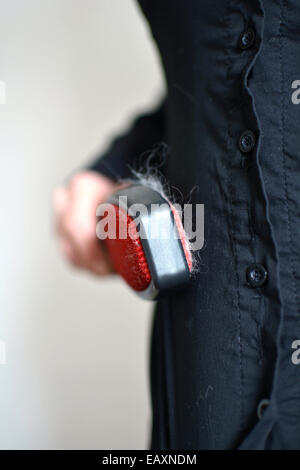 Spazzolare la camicia con una spazzola per rimuovere il pelo di gatto, prima di andare al lavoro Foto Stock