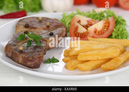 Tritare la carne di maiale bistecca braciola pasto a base di carne con patate fritte, verdure e la lattuga su piastra Foto Stock